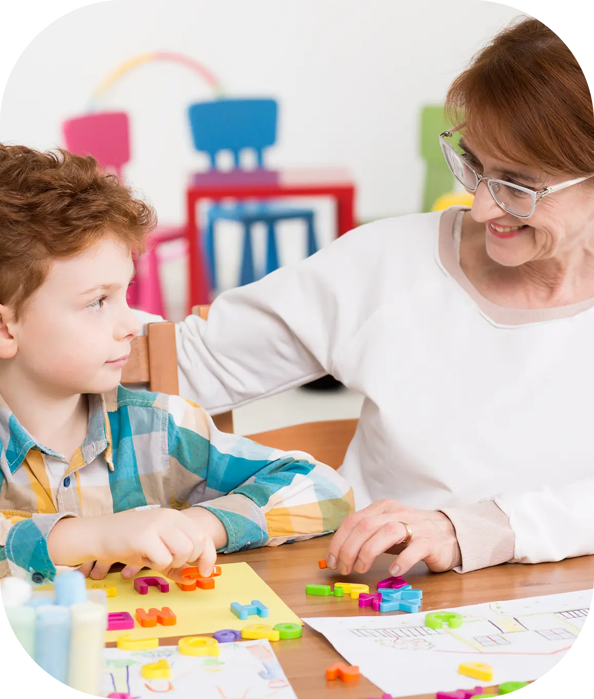 Rectangle 338 Teacher and child playing with colorful blocks.