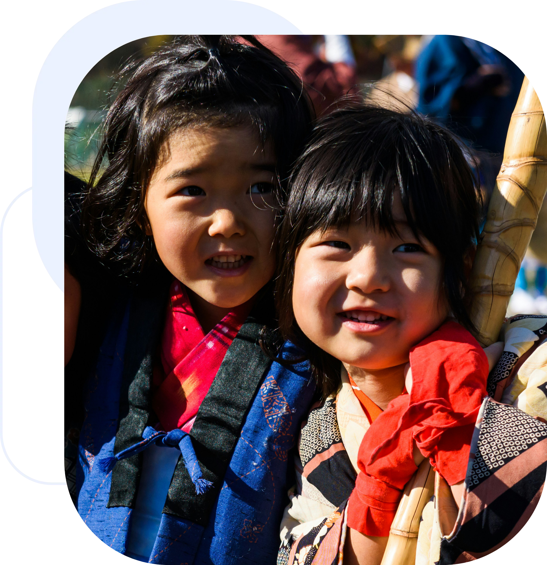 Frame-2095584996-1 (2) Two young girls smiling outdoors in colorful clothing.